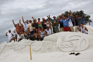 The master sand sculptors who took part in the Siesta Key Crystal Classic cheer atop their group carve – a sand sculpture highlighting event partners and sponsors, on Nov. 15 at Siesta Beach.