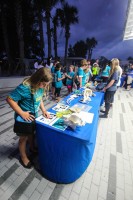 A group of young children are interacting at a table with assorted marine science display and interactive materials.