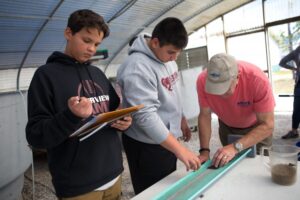 Two Riverview high school students take notes as they learn to accurately measure juvenile fish grown in one of Mote's covered greenhouses containing specially designed aquaculture tanks.