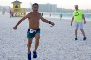 Male winner of the 5K, Hector Gozman, runs across the sand.