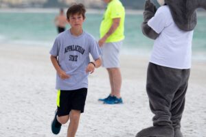 1 Mile walk/run male winner, Saxton Riggs, age 12, runs across the sand.