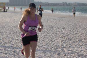 Female winner of the 5K, Joy Younkin, runs across the sand.