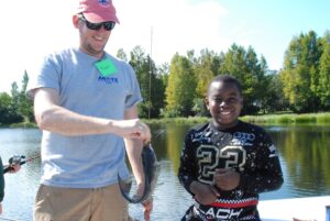 Mote's Dr. Ryan Schloesser and Brentwood Elementary student Najaden Holloway show off the fish that Holloway caught in Mote's pond. Credit: Mote Marine Laboratory