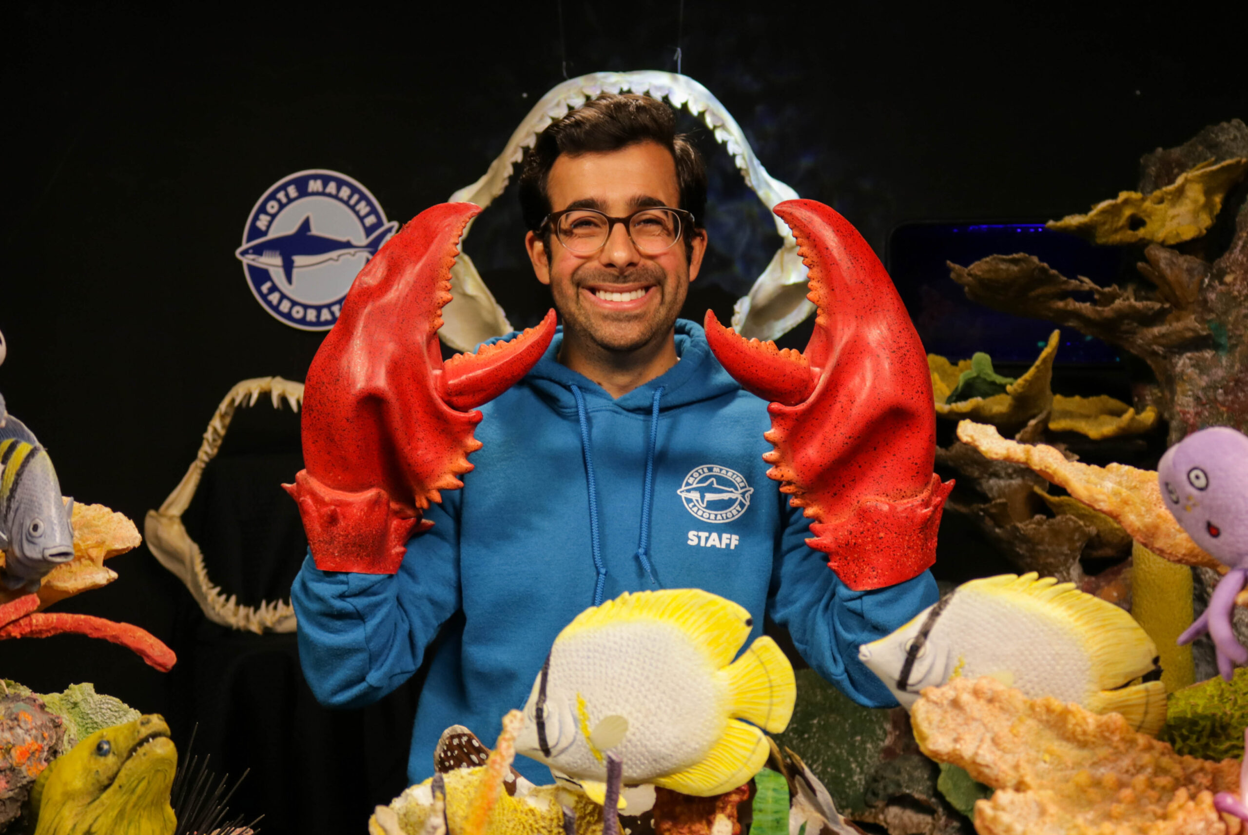 Mote Educator poses with crab claws for virtually learning class.