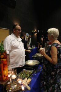 Chef Jamil Pineda of Michael's on East takes a break from serving up a lionfish dishes to chat with a guest at the Lionfish Derby reception. The serving table is decorated with lit candles and a vegetable float.