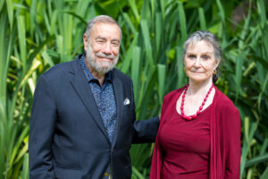 Drs. Andrew and Judith Economos pose in formal wear in front of tall, lush reeds. 