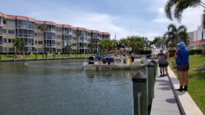 A small crowd gathers to watch the capture of the distressed manatee near Harbor Towers Yacht and Racquet Club. A small boat has corralled the manatee with a floating net.