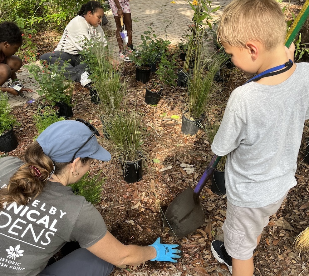 Several children help plant native flowers and grasses.