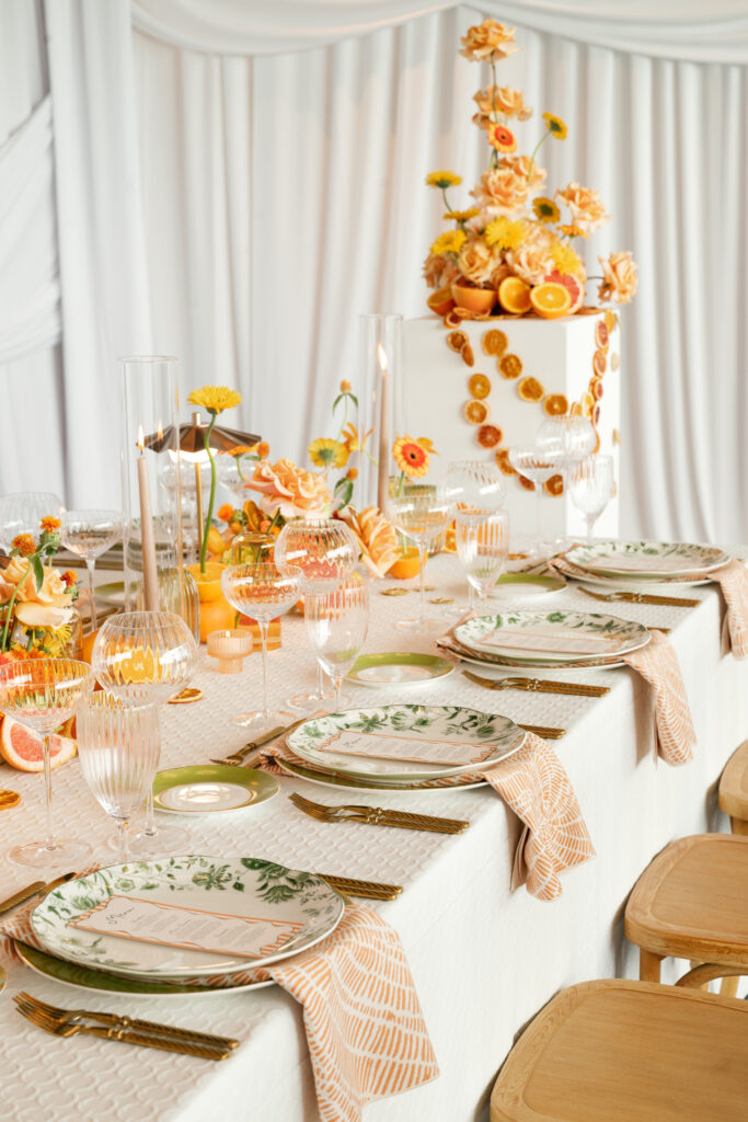 a long banquet table with beautiful orange floral decor