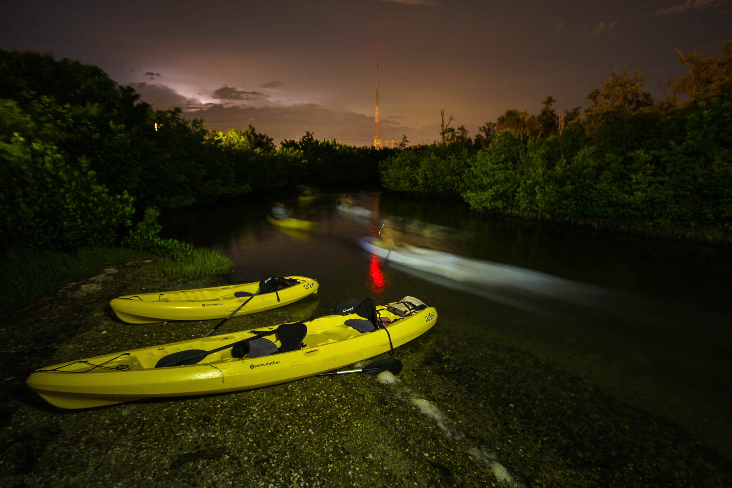 Kayaks by river at night.