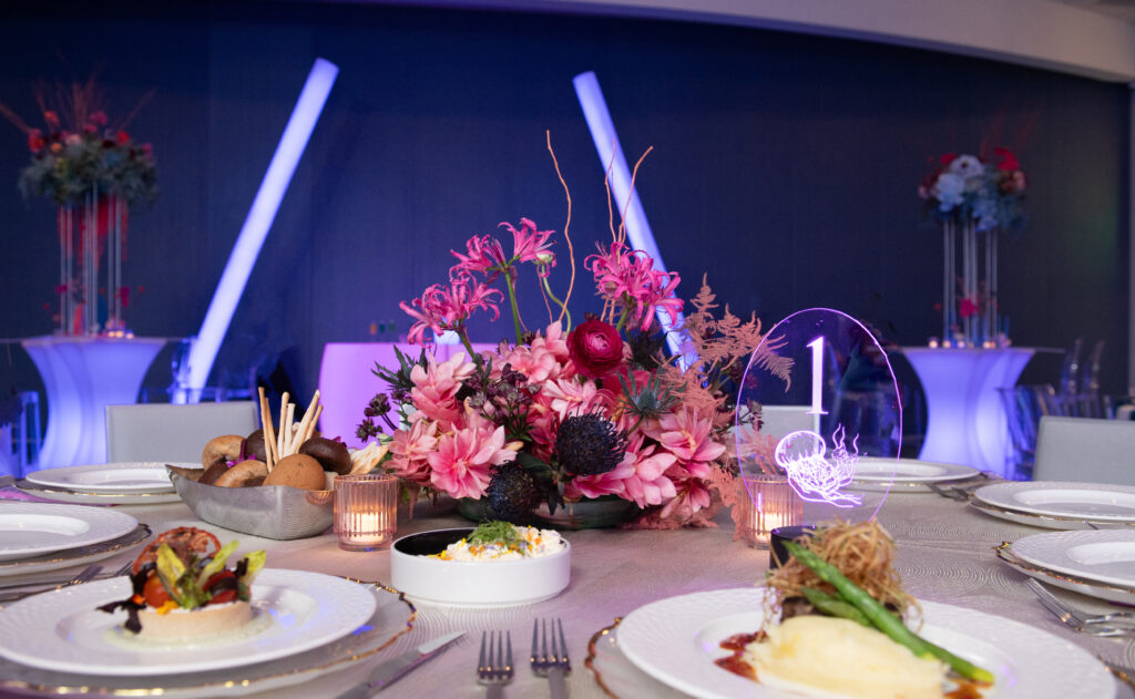 A large room features a bar and some cocktail tables set up with funky decor, and food on a banquet table