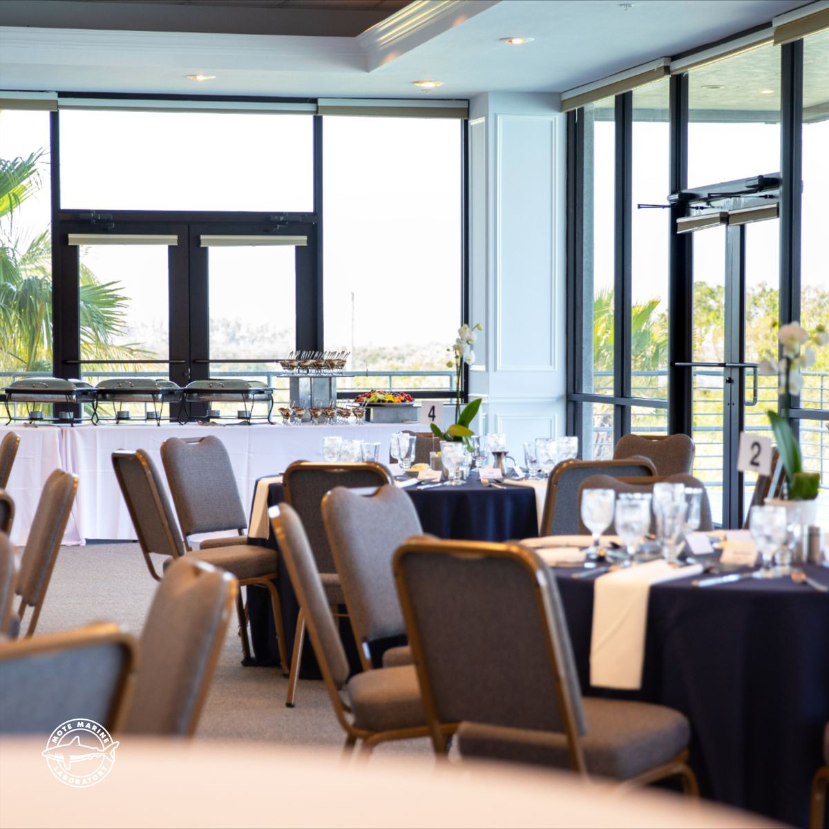 Banquet Tables set up in a room with a wall of windows overlooking the Sarasota gulf