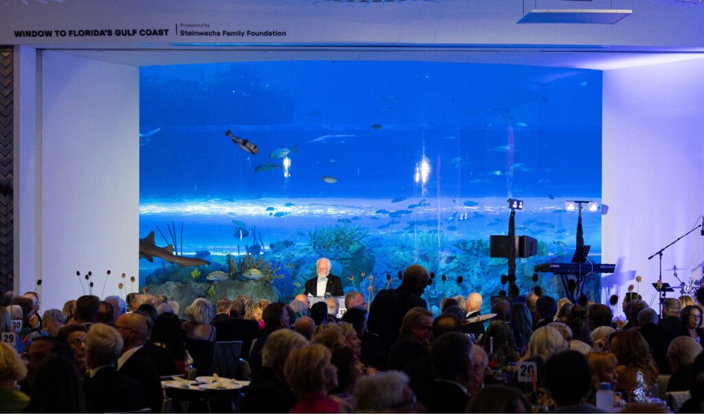 Mote President and CEO, Dr. Michael P. Crosby, speaking at Oceanic Evening in front of Florida's Gulf Waters Exhibit